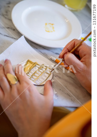 Woman painting small round canvas with fine brush at table 131677199