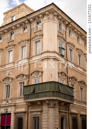 Historic European building facade with ornate windows and green enclosed balcony in Rome 131677201