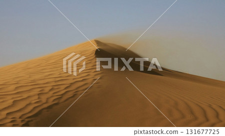 Sand blowing over sand dunes in wind Sand blowing over sand dunes in wind 131677725