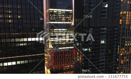 Skycrappers with reflection in glass windows city lights at night Skycrappers with reflection in glass windows city lights at night 131677755