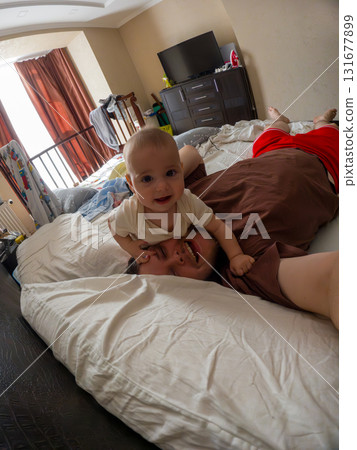 Father and Baby Playfully Bonding on Bed Father and Baby Playfully Bonding on Bed 131677899