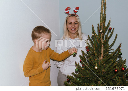 Christmas, house and hug with mother, son and bonding together with gift, decoration and care in lounge. Xmas tree, family and parent with boy, embrace and present with happiness, holiday and festive 131677971