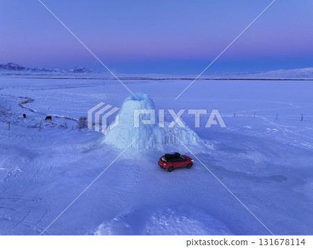 Red car exploring frozen ice geyser landscape at winter sunset, Kazakhstan 131678114