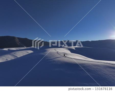 Solo adventurer hiking through snowy winter mountain landscape, Kazakhstan 131678116