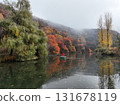 Man rowing boat on misty autumn lake with colorful trees, Kazakhstan 131678119