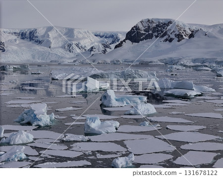 Antarctica ocean with scattered icebergs and mountains 131678122