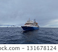 Expedition vessel navigating antarctic waters near icy landscape, Antarctica 131678124