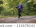 Active woman hiking in forest with trekking poles, enjoying outdoor adventure 131678142