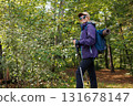 Smiling hiker with backpack and trekking poles in summer forest 131678147