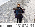 Back view of hiker woman climbing sandy hill with backpack 131678154