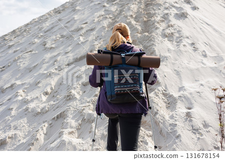 Back view of hiker woman climbing sandy hill with backpack Back view of hiker woman climbing sandy hill with backpack 131678154