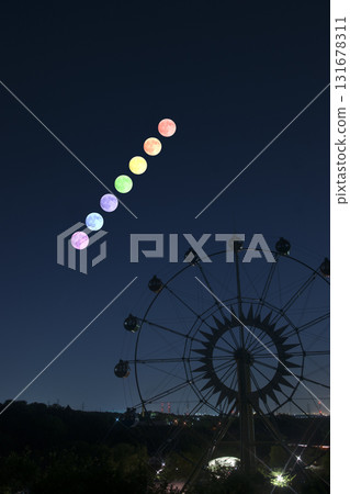 A ferris wheel floating in the rainbow-colored full moon sky 131678311