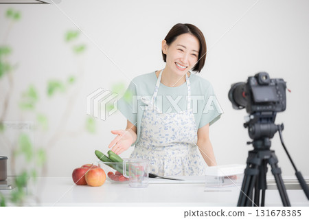 A housewife-like YouTuber filming herself cooking 131678385