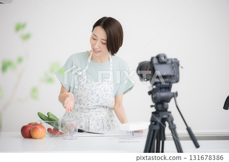 A housewife-like YouTuber filming herself cooking A housewife-like YouTuber filming herself cooking 131678386