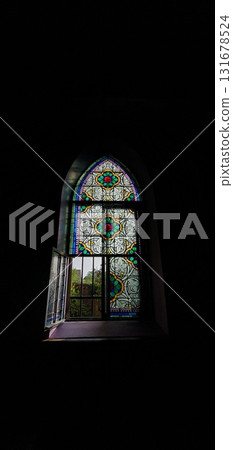 Half-opened stained glass window in a medieval church in Alsace along a hiking trail, mobile photo. Concept of architecture, heritage, religion, authenticity. 131678524