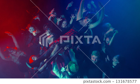 Woman crowd surfing above cheering Halloween party audience 131678577