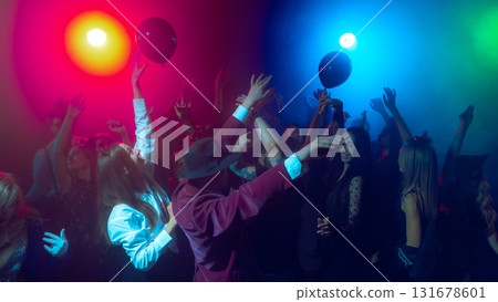 People reaching for black balloons at neon Halloween dance floor 131678601