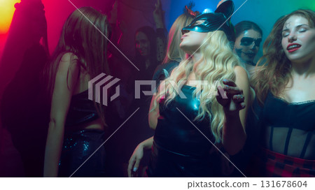 Group of people in costumes dancing under neon lights at club Group of people in costumes dancing under neon lights at club 131678604