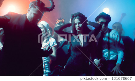 Young woman in black dress dancing at nightclub Halloween party with dramatic lights 131678607