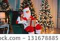 Santa gives a gift to a child for Christmas. little girl gets excited and happy while opening Christmas gift boxes with presents from Santa. 131678885