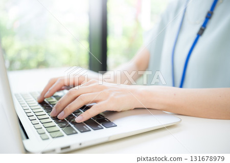 A woman operating a computer in a beautiful semi-backlit office (no face) 131678979