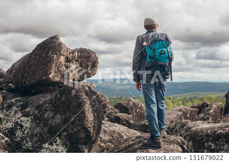 A tourist with a backpack stands on the top of the mountain and admires the view. The concept of sports and active life. 131679022