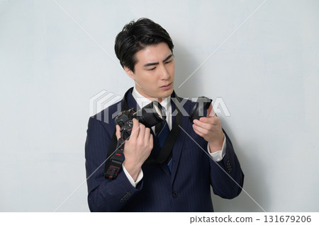A man in a suit holding a camera and worrying A man in a suit holding a camera and worrying 131679206