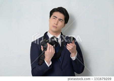 一個穿著西裝的男人拿著相機擔心 131679209