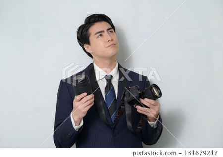 A man in a suit holding a camera and worrying A man in a suit holding a camera and worrying 131679212