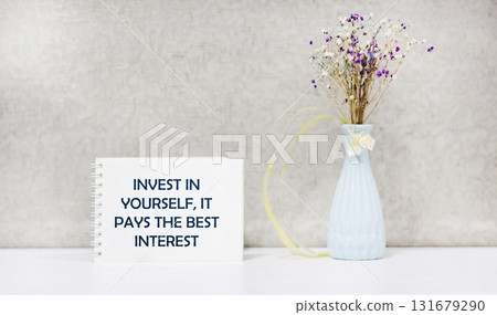 The inscription Invest in yourself, it pays the best interest, appears on a white notebook. The inscription Invest in yourself, it pays the best interest, appears on a white notebook. 131679290
