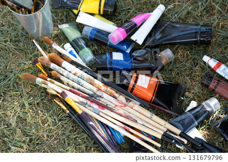 Artistic mess of acrylic paint tubes and assorted brushes scattered on grass, colorful textures and creative tools for crafting, hobby, and fine art projects Artistic mess of acrylic paint tubes and assorted brushes scattered on grass, colorful textures and creative tools for crafting, hobby, and fine art projects 131679796