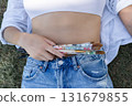Closeup of a woman's hand tucking colourful used paintbrushes into blue jeans waistband, creative lifestyle detail with texture and casual fashion vibe, macro crop. 131679855