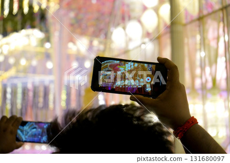 Person Recording Brightly Lit Durga Puja Pandal Decoration with Smartphone at Night Person Recording Brightly Lit Durga Puja Pandal Decoration with Smartphone at Night 131680097