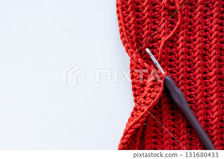Red crochet project with hook on white background with copy space for text Red crochet project with hook on white background with copy space for text 131680433