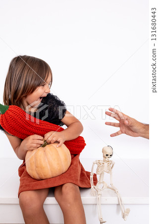 Young caucasian girl enjoying Halloween with pumpkin and skeleton toy with copy space for text Young caucasian girl enjoying Halloween with pumpkin and skeleton toy with copy space for text 131680443