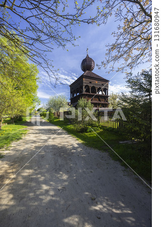 Wooden belfry, path and trees, rural spring landscape 131680947