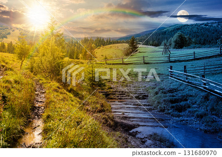 mountainous rural landscape in autumn. day and night time change concept. wooden fence near the path through grassy meadow on the hillside. scenery with fir forest on the mountains with sun and moon 131680970