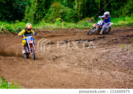 uzhhorod, ukraine - may 21, 2017: junior mx rider turns on a corner. motocross track through forest. extreme sport with flying dirt during accelerating 131680975