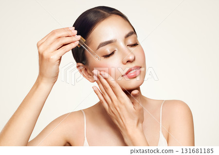 Young beautiful woman applying face serum 131681185