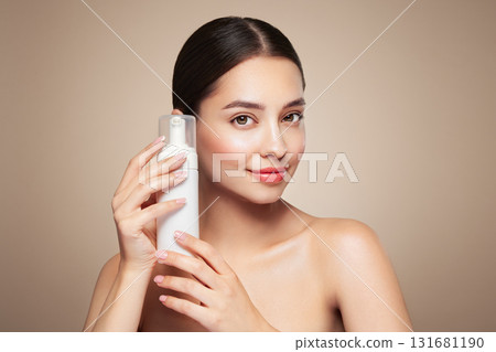 Young woman shows off a bottle with a foam dispenser for washing Young woman shows off a bottle with a foam dispenser for washing 131681190