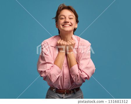 Smiling woman with clenched hands expressing excitement and gratitude 131681312