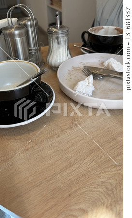 Empty coffee cups and dirty plates on a wooden cafe table after a meal Empty coffee cups and dirty plates on a wooden cafe table after a meal 131681337