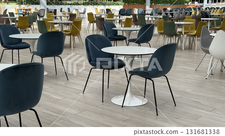 Empty cafeteria with modern furniture and colorful chairs in a spacious setting during daytime Empty cafeteria with modern furniture and colorful chairs in a spacious setting during daytime 131681338