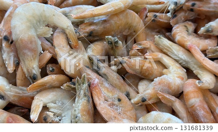 Frozen shrimps piled closely, showcasing seafood texture and detail for culinary backgrounds Frozen shrimps piled closely, showcasing seafood texture and detail for culinary backgrounds 131681339