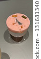 Glass of layered pink and white yogurt dessert with fruit pieces on smooth background 131681340