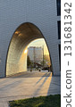 Sunset light casting shadows through modern urban archway, with grass and building in view 131681342