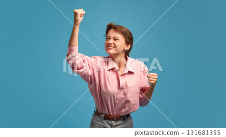 Determined woman raising fist with confident power and motivation Determined woman raising fist with confident power and motivation 131681355