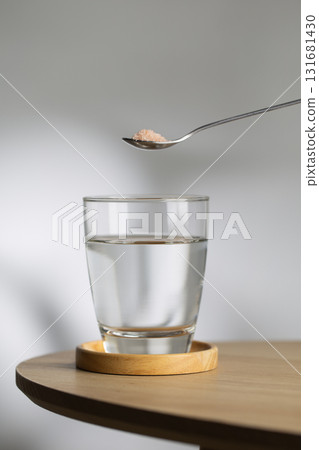 A spoon of Himalayan salt is being added to a glass of drinking water. A spoon of Himalayan salt is being added to a glass of drinking water. 131681430