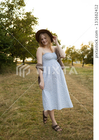 Pregnant woman walking outdoors in summer dress at sunset 131682412