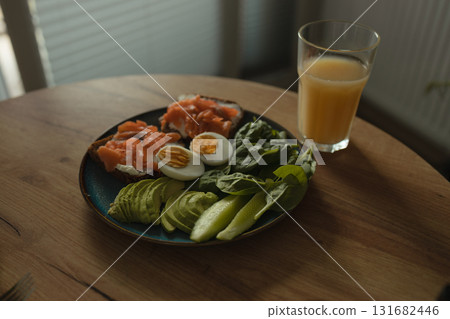 Healthy breakfast with salmon, egg, avocado, greens, and orange juice 131682446
